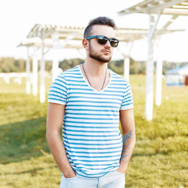 Beau homme dans une chemise élégante et des lunettes de soleil reposant sur la plage . — Photo