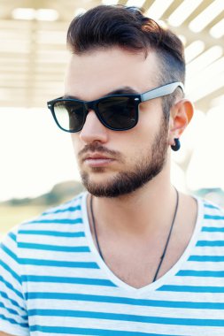 Sahilde sakallı güneş gözlüklü yakışıklı hipster adamın yaz portresi.