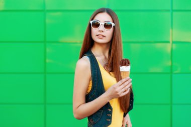 Yeşil duvarın yanında dondurması olan güzel genç bir kadın..