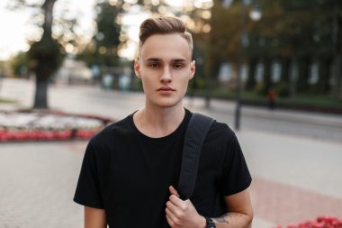 Şehrin arka planda bir sırt çantası ile bir saç kesimi ile yakışıklı genç adam.