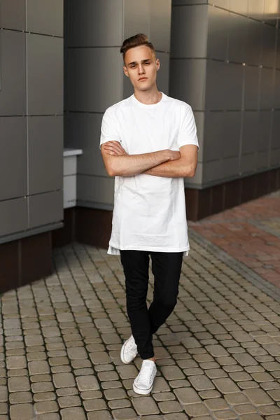 Joven chico guapo en ropa elegante y zapatos posando cerca del edificio moderno . — Foto de Stock