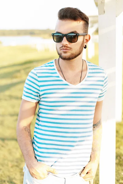 Knappe man in een stijlvolle zomer t-shirt rustend op het strand. — Stockfoto