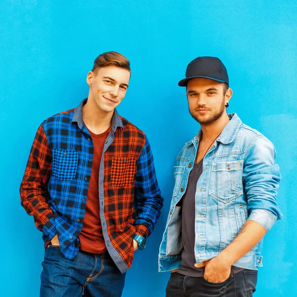 Deux beaux et élégants meilleurs amis masculins près du mur bleu . — Photo