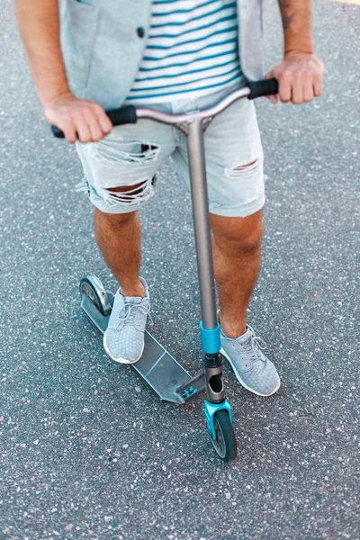 Calcia lo scooter sull'asfalto. Uomo alla moda in sella a uno scooter . — Foto Stock