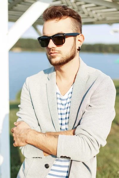 Schöner Mann mit Bart, Sonnenbrille und Jacke am Strand — Stockfoto