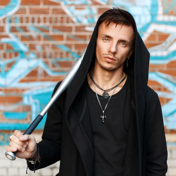Hood yakınındaki duvara graffiti ile siyah giysili bir sopayla yakışıklı adam