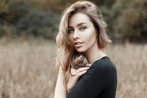 Retrato de uma jovem mulher em uma camisa preta em um fundo da natureza — Fotografia de Stock
