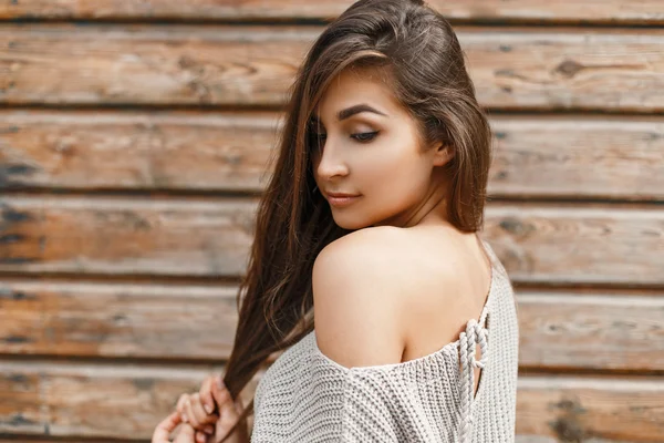 Piękna młoda kobieta w szary sweter w pobliżu drewniana ściana — Zdjęcie stockowe