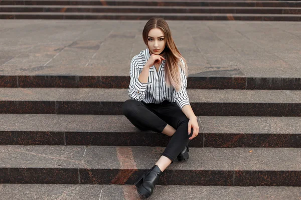 Hermosa modelo de chica en una ropa de moda sentado en las escaleras — Foto de Stock