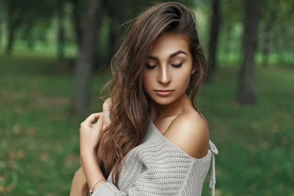 Hermosa chica modelo joven con peinado en un suéter de punto en el parque — Foto de Stock