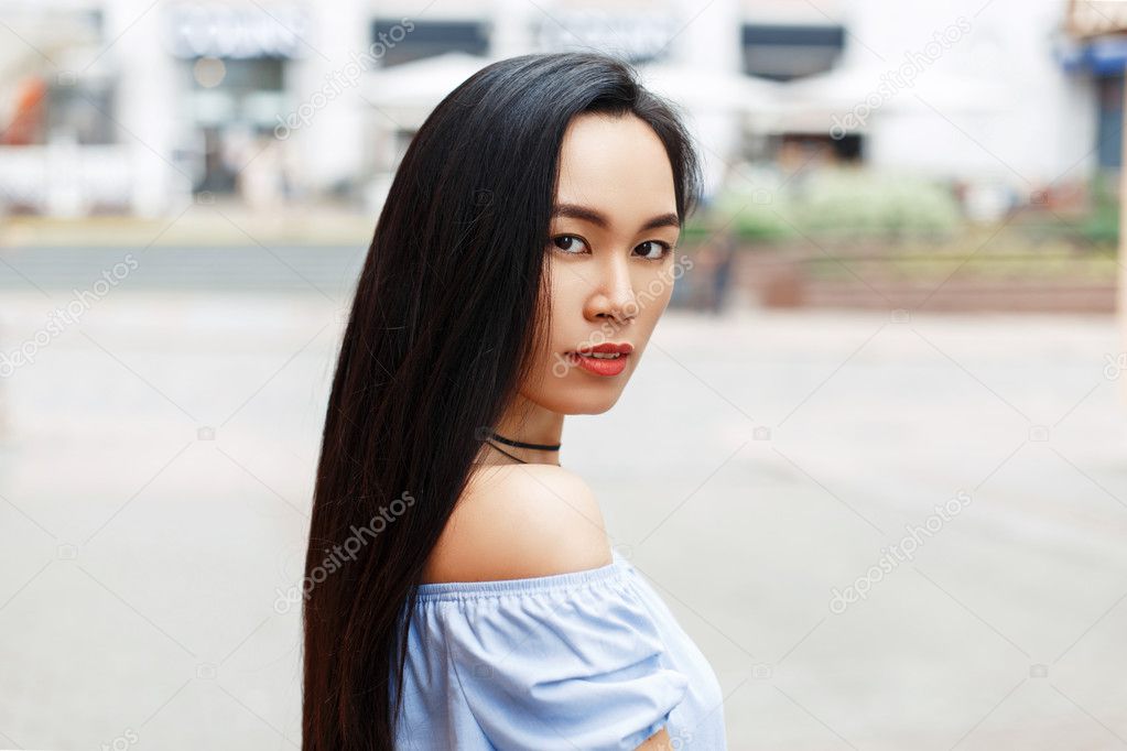 Beautiful young Asian woman with bare shoulders in the city