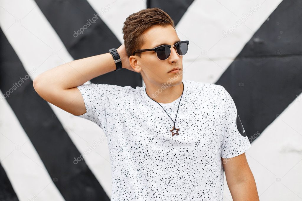 Stylish handsome man in sunglasses posing on background lines