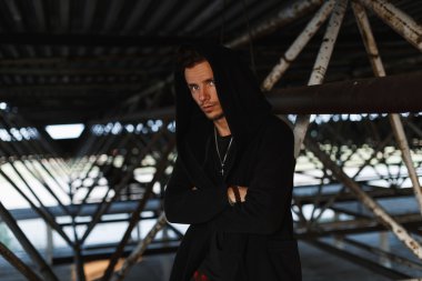 Metal yapılar yakınındaki bir kukuleta ile şık bir cüppeli moda yakışıklı