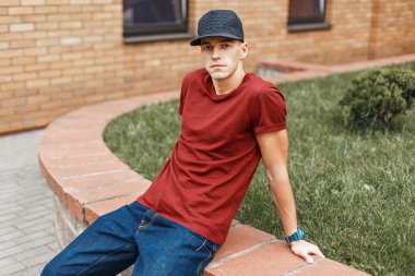 Yıldızlar ve t-shirt ile siyah şapkalı şık yakışıklı Amerikalı adam sokakta dinlenme.