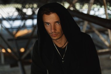 Yakışıklı genç bir kukuleta ile siyah bir elbise içinde.