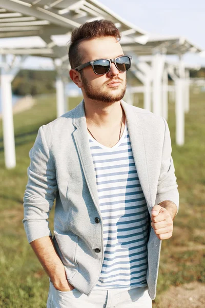 Knappe hipster kerel in trendy jasje poseren op het strand. — Stockfoto