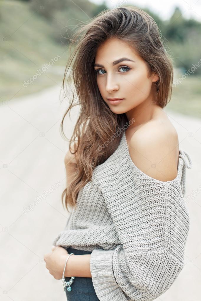 Young pretty woman with curly hairstyle in vintage knitted sweater with a naked shoulder