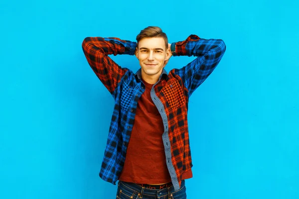 Όμορφος ευτυχισμένος νέος σε μοντέρνο σακάκι κοντά σε ένα φωτεινό μπλε τοίχο — Φωτογραφία Αρχείου