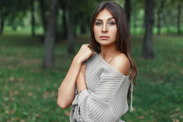 Piękna młoda kobieta z ładną buzią w szary sweter w parku — Zdjęcie stockowe