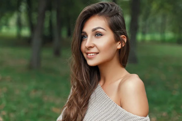 Szczęśliwy, piękna, młoda dziewczyna w sweter z uśmiechem na tle parku — Zdjęcie stockowe