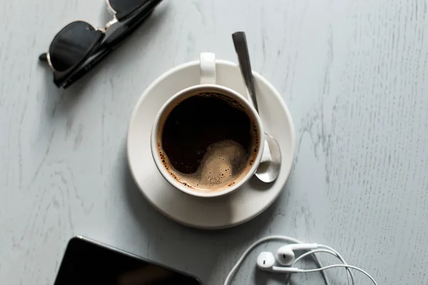 Káva na dřevěný stůl s telefonem s sluchátka a brýle — Stock fotografie