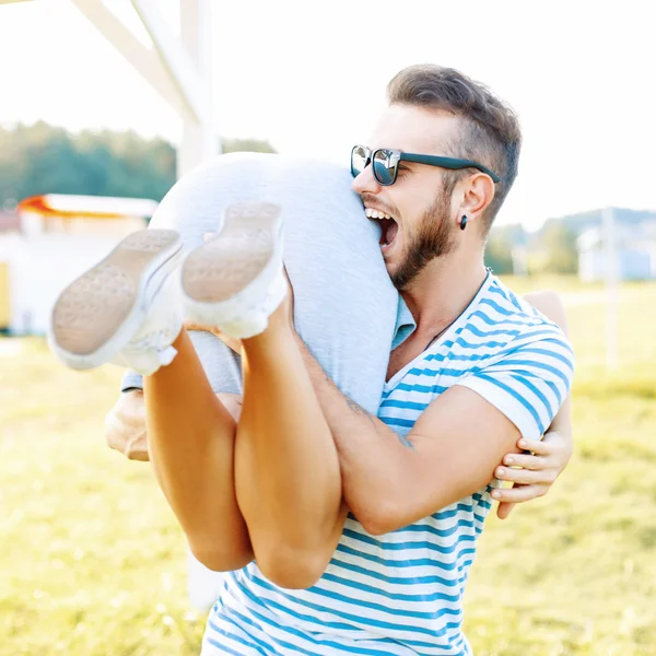 Young beautiful hipster couple relaxing on the beach. Handsome man and woman have fun on a summer day. Man bites the girl's ass — Stockfoto