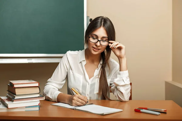 Vacker ung kvinna med glasögon att studera vid universitet, läsa böcker och skriver i en anteckningsbok. — Stockfoto