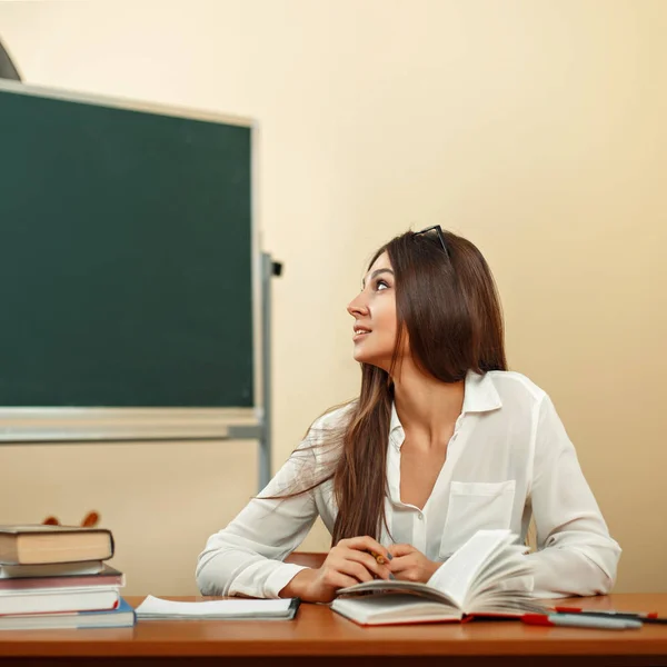 Beautiful young girl in white blouse looks at the chalkboard — Stock Photo, Image