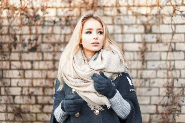 Mladá krásná blondýnka s módní teplá šála poblíž cihlová zeď — Stock fotografie