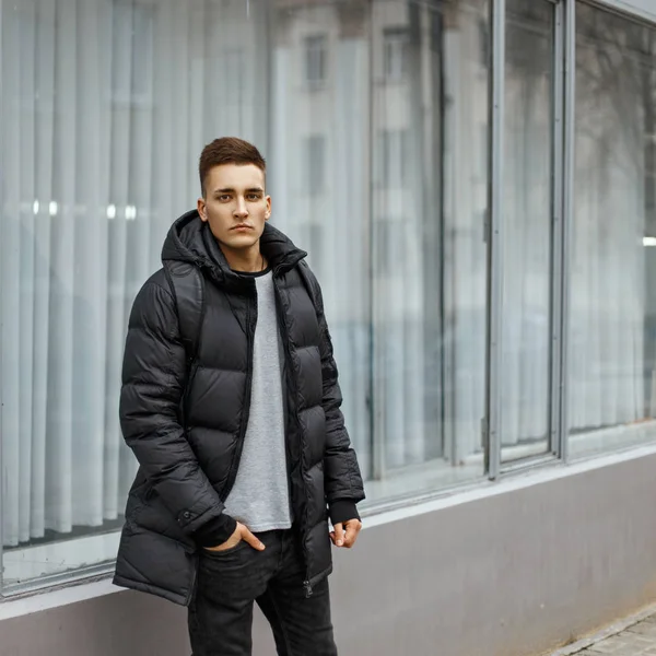 Młody człowiek z płaszczem modne zimowe pozowanie w pobliżu okna — Zdjęcie stockowe