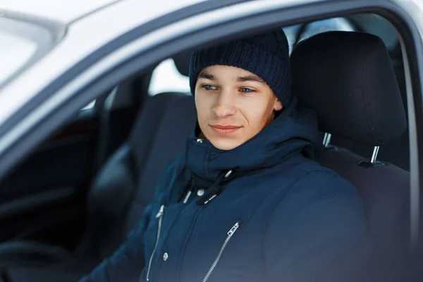 Jovem macho em roupas de inverno sentado em um carro — Fotografia de Stock