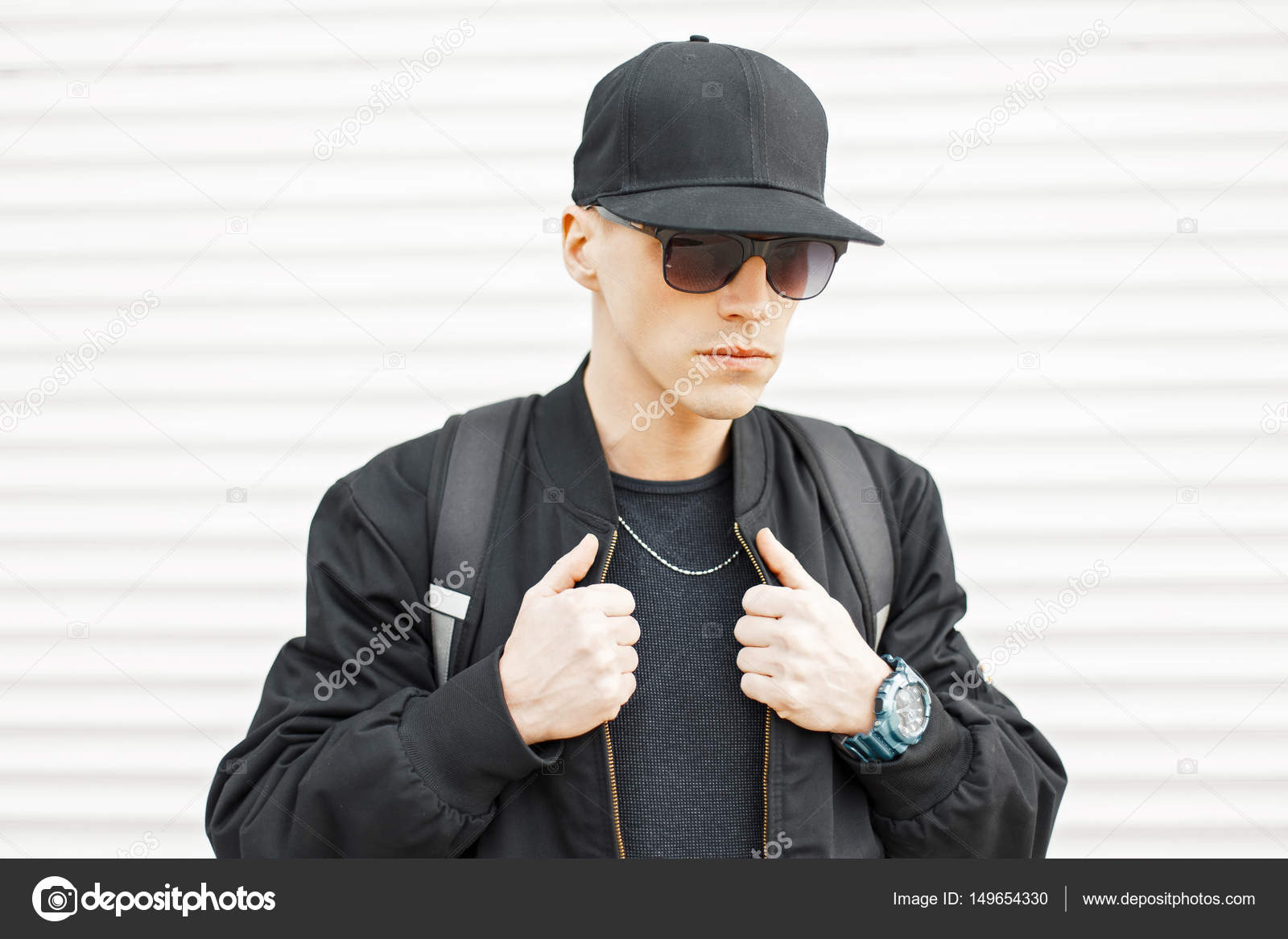 Handsome stylish man in sunglasses and a black baseball cap near a