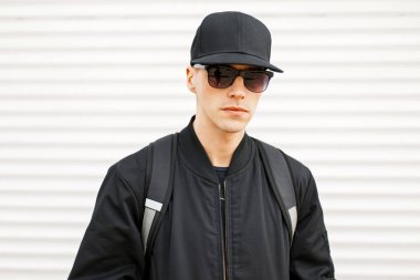 Siyah giysiler ve şık kap beyaz Metalden güneşlik yakınındaki yakışıklı adam