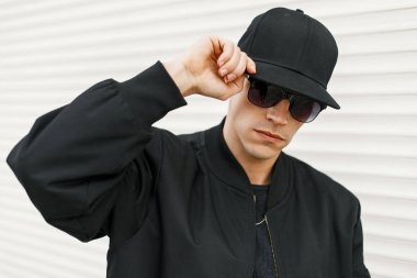 Yakışıklı adam siyah moda gözlük ve beyaz duvara yakın poz siyah beysbol şapkası