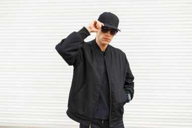 Siyah moda modern giysiler bir beyaz metal duvarının yakınında şık yakışıklı adam