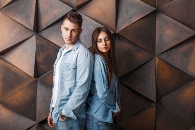 Şık denim giysili genç şık çift ahşap bir duvara yakın dur