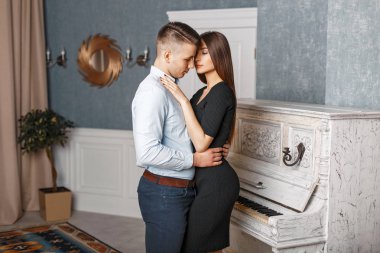 Şık giysiler içinde zarif genç çift bir vintage beyaz piyano hugs