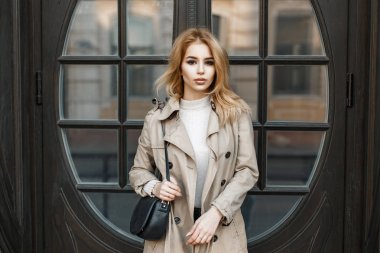 Siyah bir çanta ile şık bir ceket genç güzel kadın otel kapının yanında duruyor