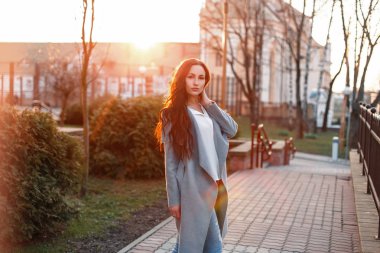 Genç kadın bir gri trendy ceket ve kot üzerinde güzel bir sunse
