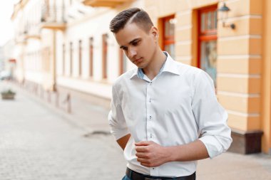 Şehirdeki şık beyaz gömlekli bir saç modeli ile moda yakışıklı adam