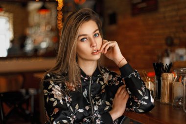 Genç kız güzel bir ceket çiçekli bir kafede bir barda oturur