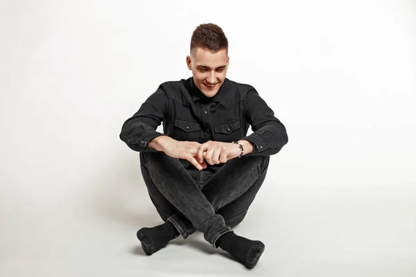 Schöner junger Mann mit einem Lächeln in schwarzem Hemd und schwarzer Jeans auf weißem Hintergrund — Stockfoto