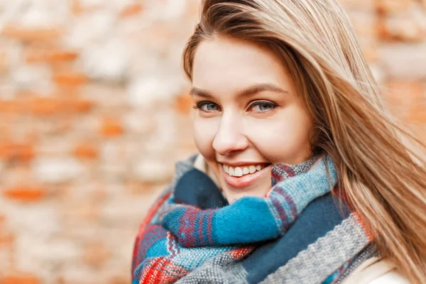 Vacker ung glad flicka leende med perfekt leende och vita tänder nära tegelvägg och tittar på kameran — Stockfoto