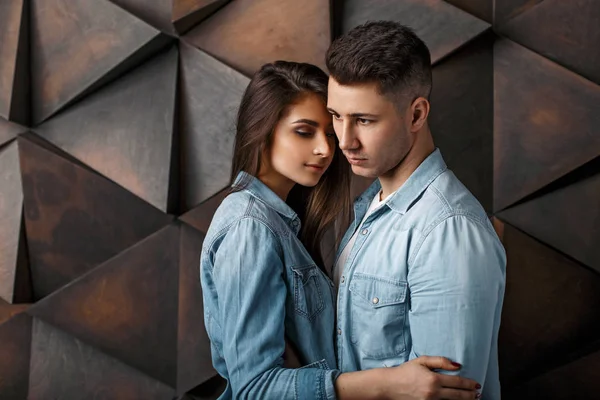 Mooie paar in jeans kleding in de studio in de buurt van een houten muur — Stockfoto