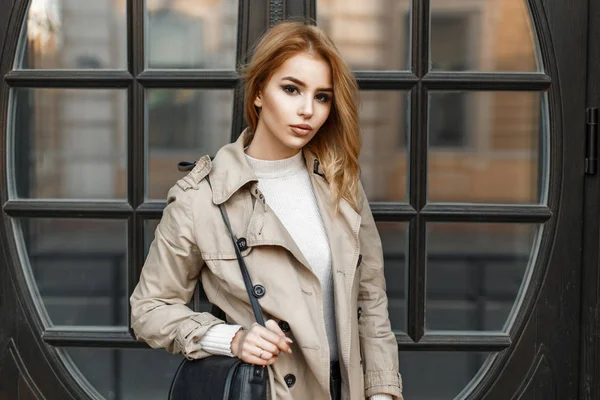 Stylish beautiful woman in a coat with a bag near the door — Stock Photo, Image