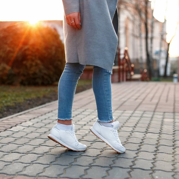 Красивые женские ноги в белых туфлях и джинсах на закате — стоковое фото