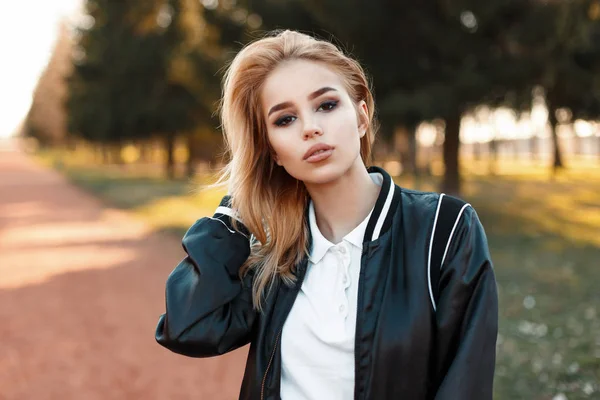 Retrato de una hermosa mujer rubia con una chaqueta de bombardero en polo blanco en un día soleado —  Fotos de Stock