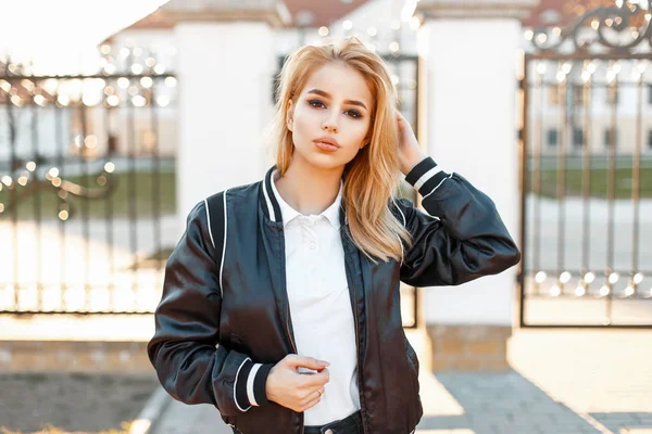 Menina loira jovem na moda em jaqueta preta e camisa de pólo branco em um dia de primavera — Fotografia de Stock