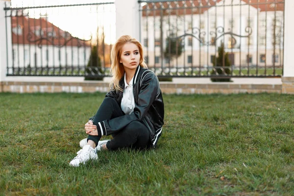 Красива студентка дівчини в стильній куртці і чорні джинси з білими кросівками в колажі на траві — стокове фото