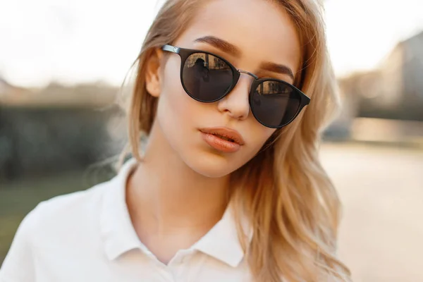 Menina bonita em óculos de sol em um dia de primavera ao pôr do sol. Retrato de uma mulher loira — Fotografia de Stock